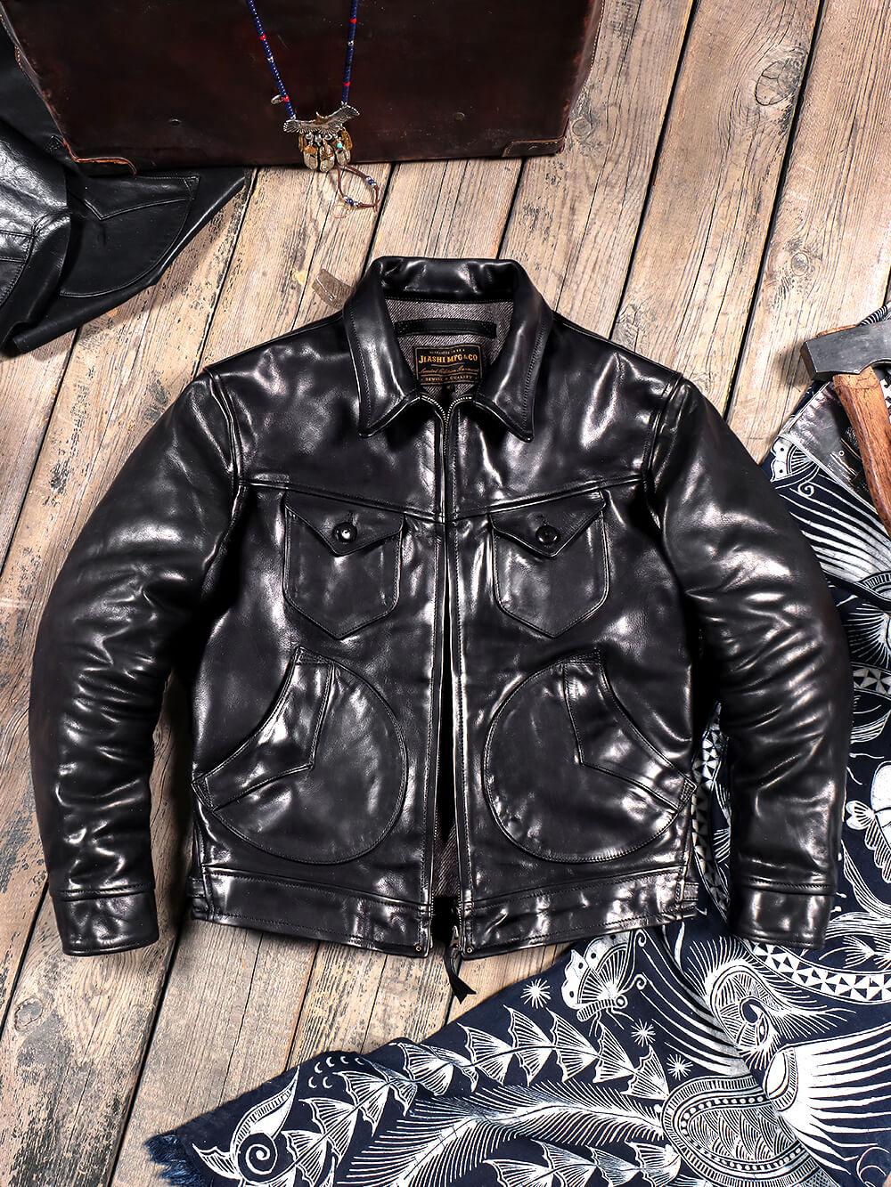 A brown Men's Mendoza leather jacket with a mandarin collar, two buttoned chest pockets, and dual lower round pockets. It includes adjustable waist buckles and a zip closure.